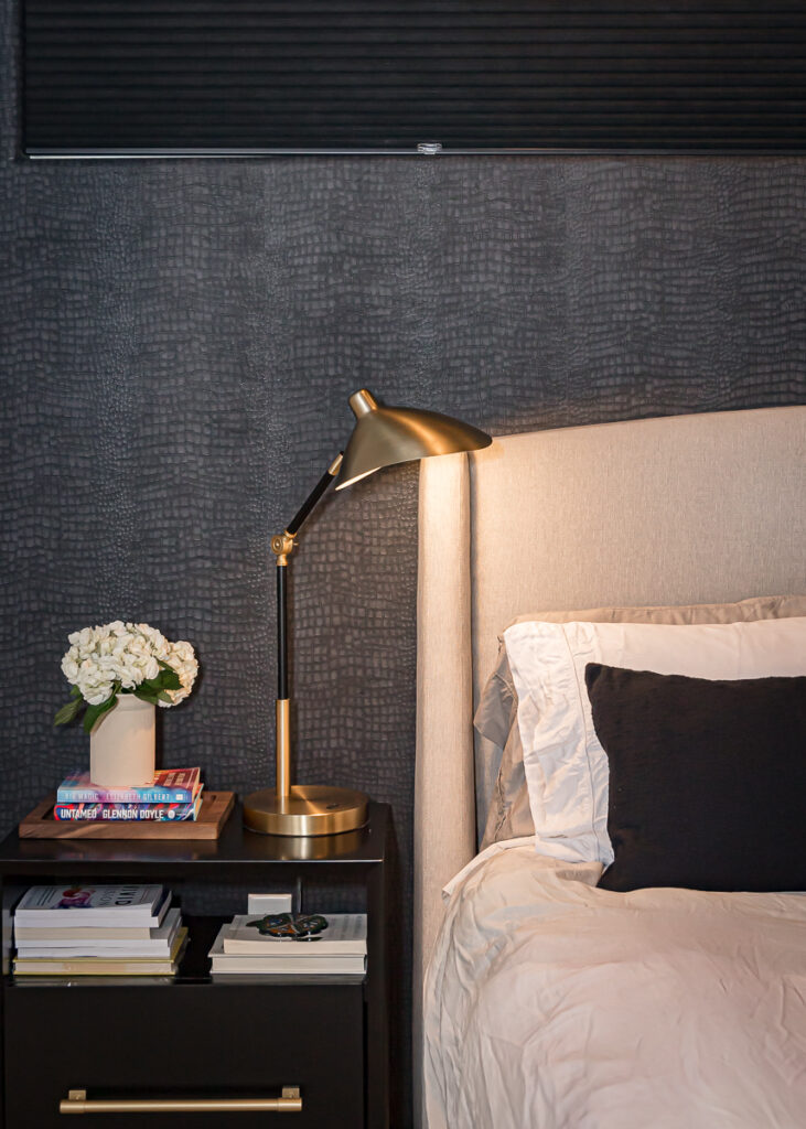 Interior design portfolio photo, nightstand with a gold lamp, books, and flowers